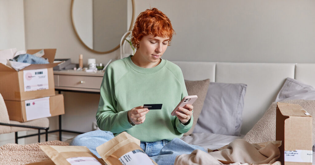 Sales control solution - young woman surrounded by eCommerce deliveries, shopping on her phone